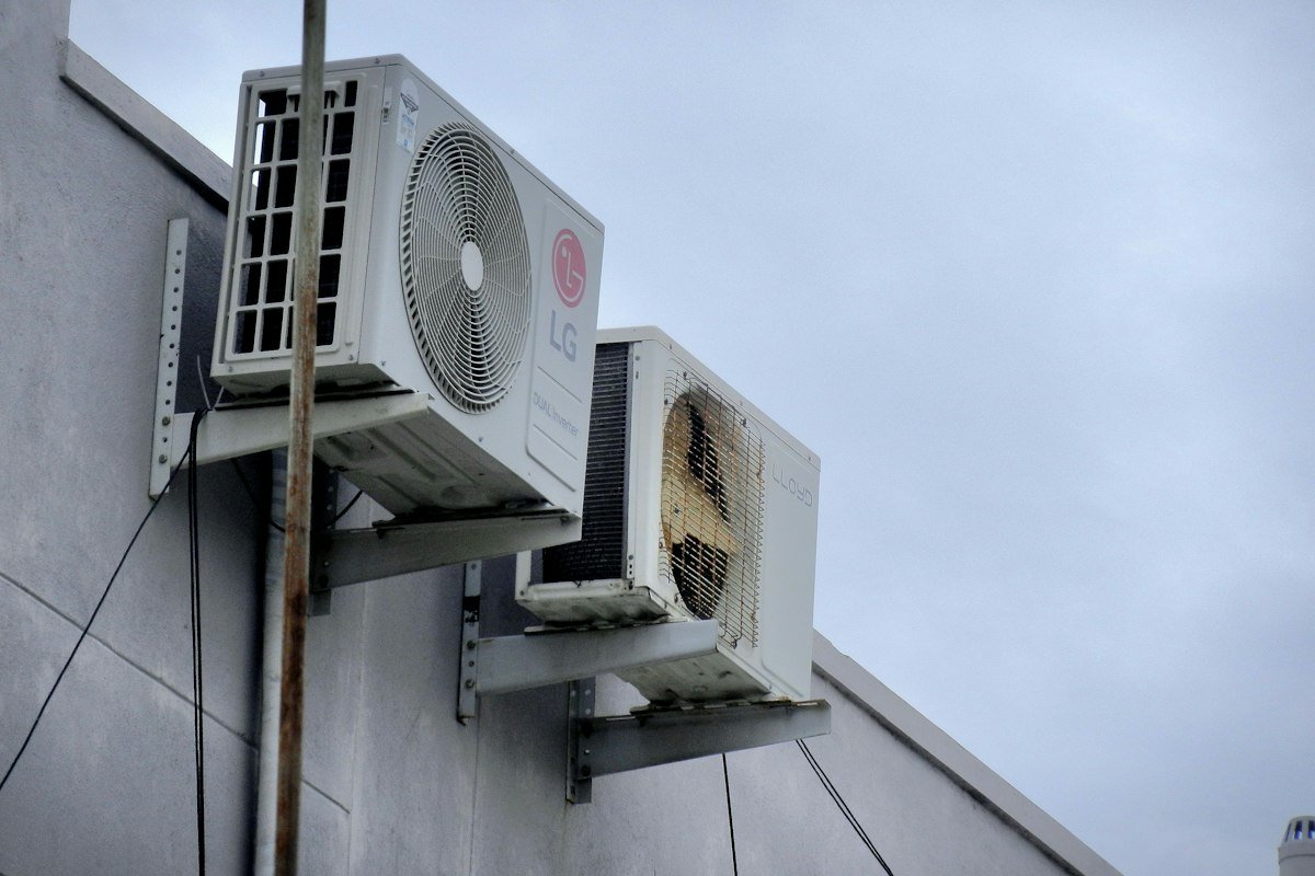 HVAC technician checking refrigerant lines on outdoor AC unit